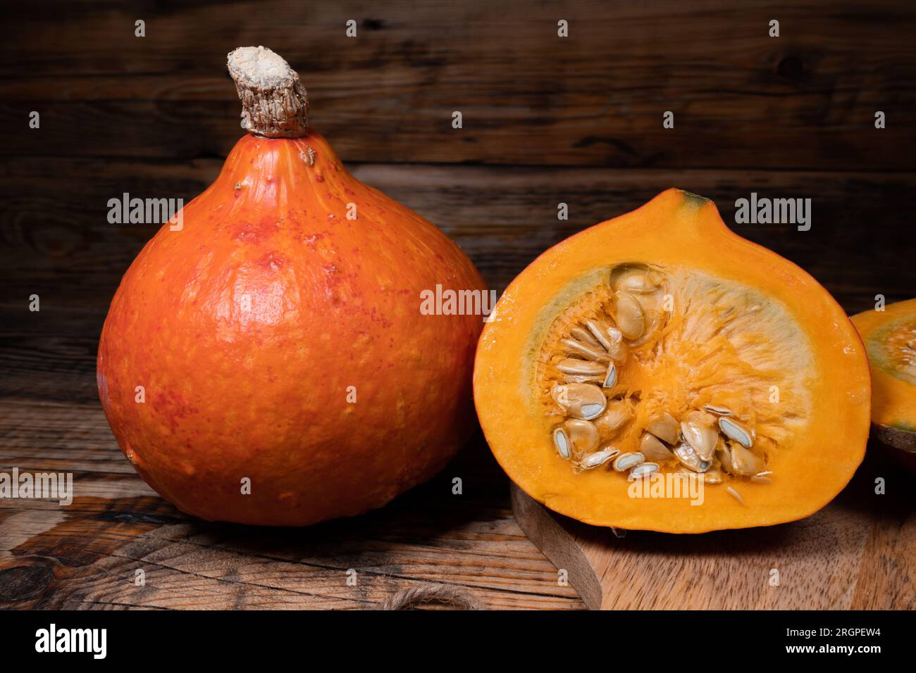 Hokkaido pumpkins on wooden background. Red kuri squash autumn fall rustic composition for Halloween or Thanksgiving. Stock Photo