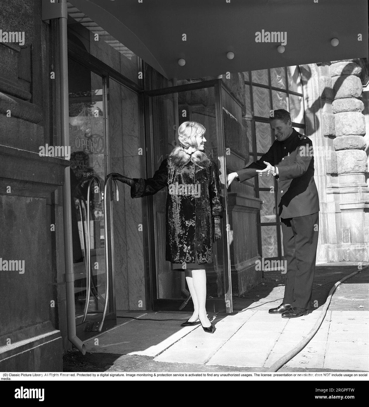 Service in the 1960s. A young fashionable dress woman is standing in the doorway of restaurant Operakällaren in Stockholm with a doorman galantly holding the door up.  Sweden 1962. Kristoffersson Ref CV87-4 Stock Photo