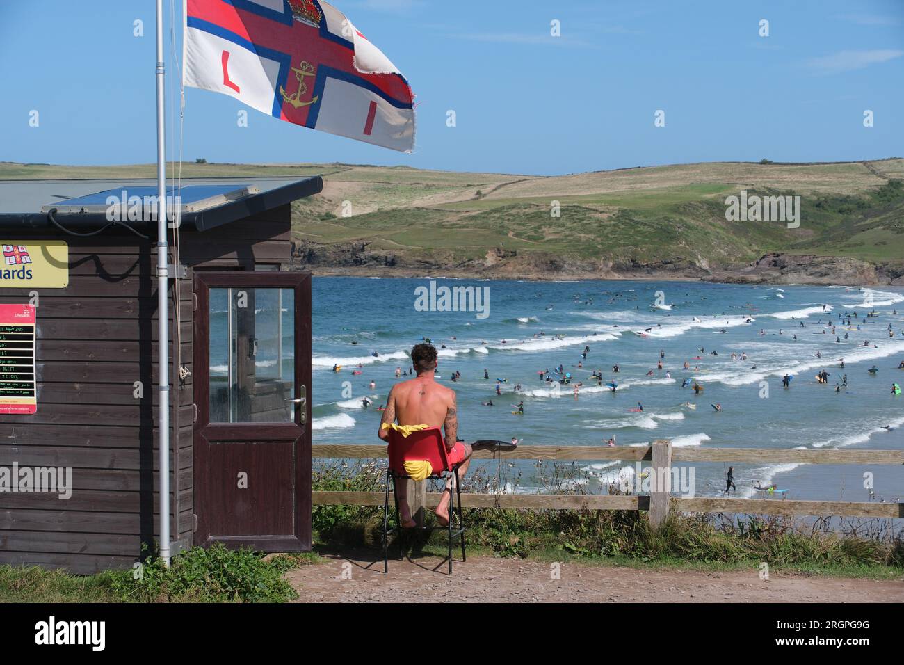 Polzeath, Cornwall, UK. 11th August 2023. A lifeguard keeping an eye on the busy sea at Polzeath this morning., as the heatwave returns briefly to Cornwall. Credit Simon Maycock / Alamy Live News. Stock Photo