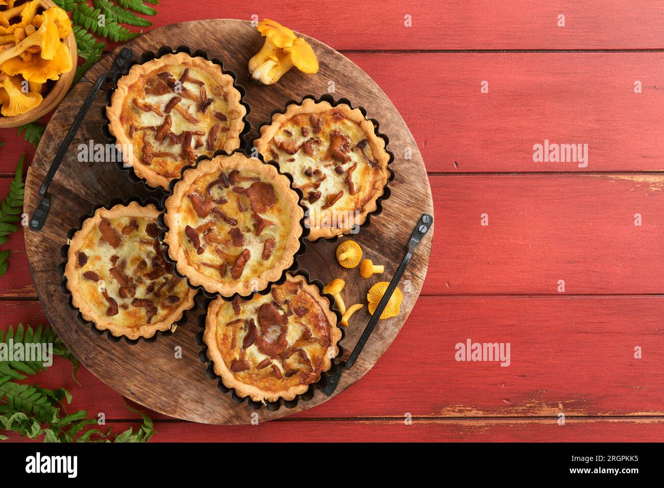Savory hands pie with chanterelle mushrooms, cream and cheese on cutting board on rustic old red wooden table background. Homemade tarts with seasonal Stock Photo