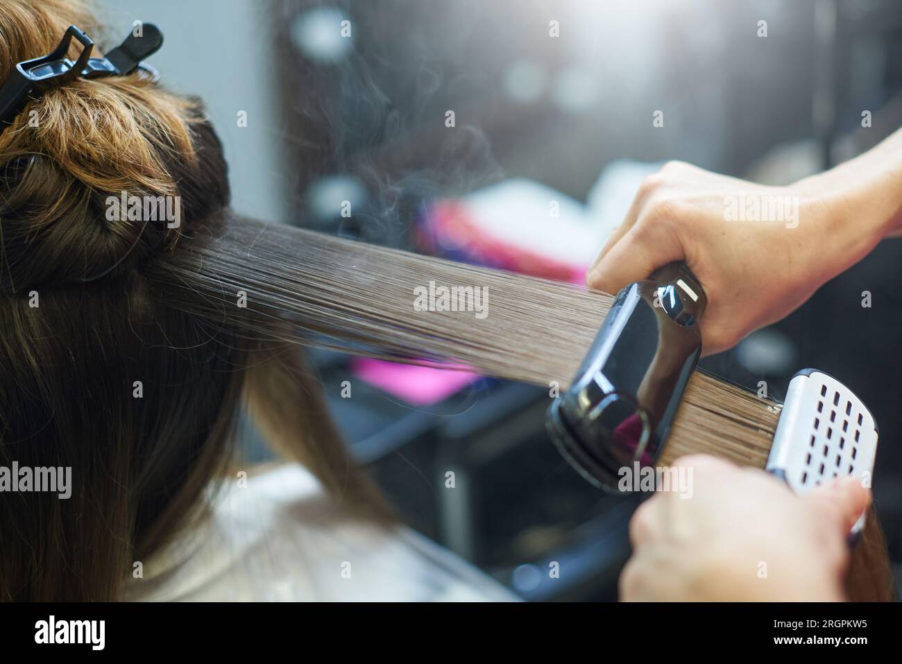 Hair straightening with keratin and a hair iron. Stock Photo
