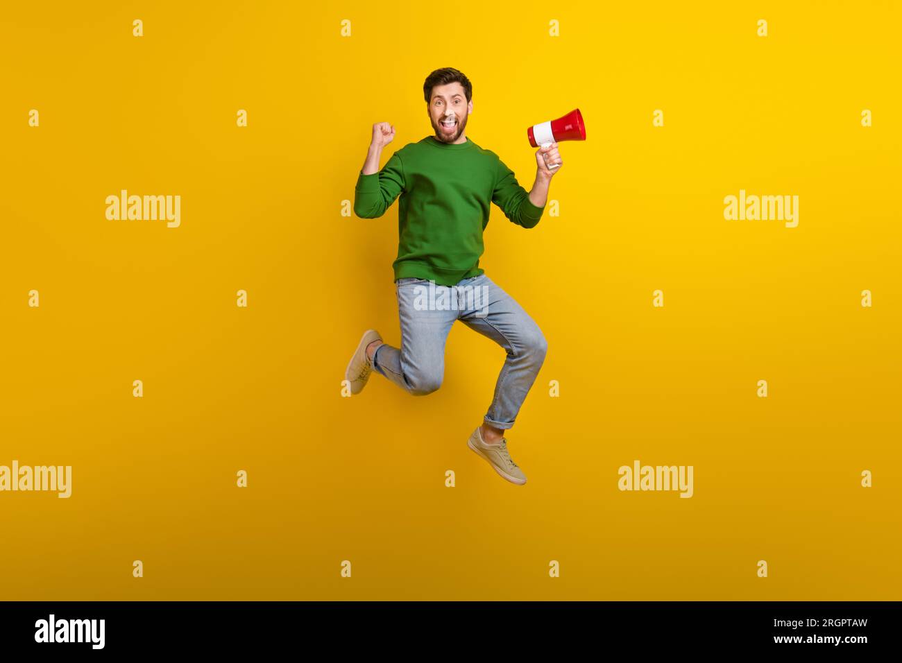 Full size photo of jumping guy fist up hooray holding megaphone bullhorn announce fist his losung win isolated on yellow color background Stock Photo