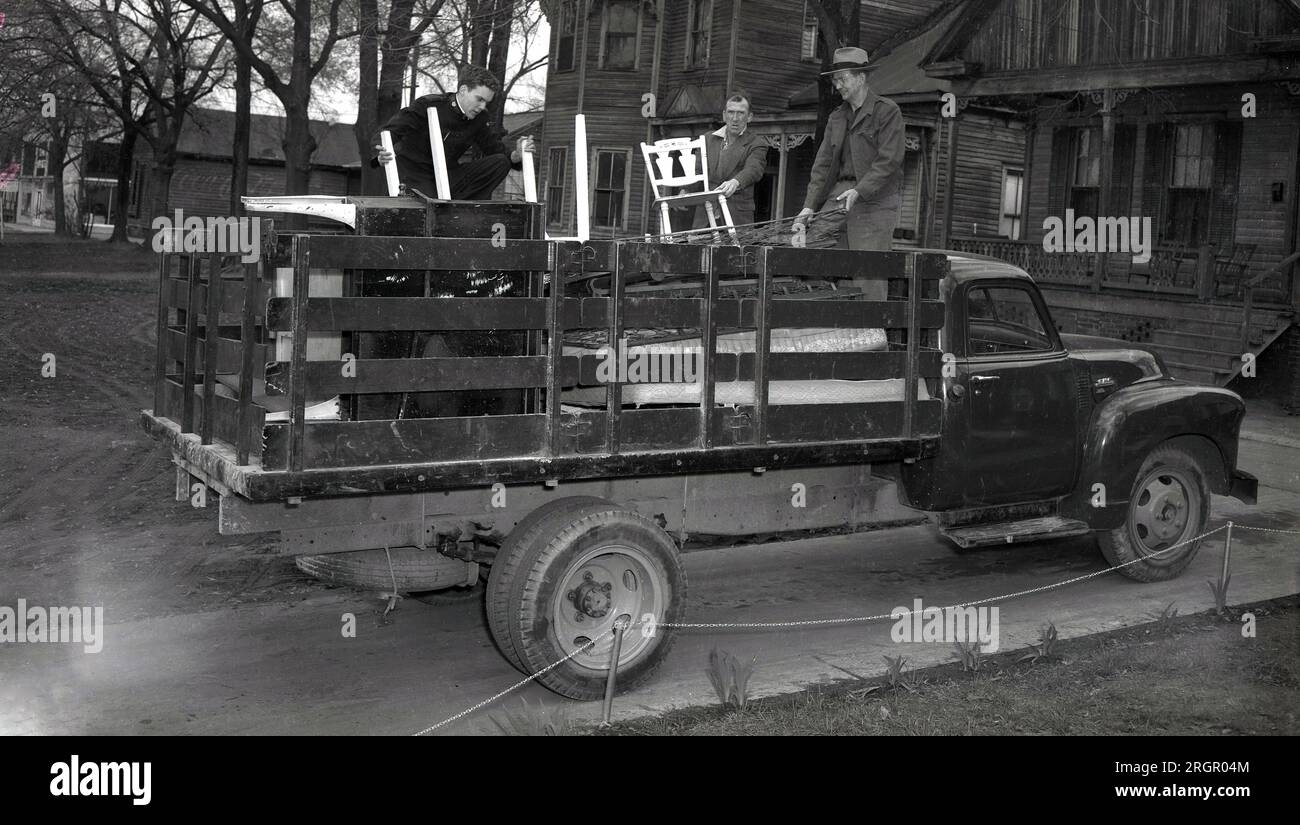 1950s, historical, members of the Salvation Army loading old furniture onto the back of a truck, collected from an old wooden-framed house in Mid-West America. Founded as a Christian Mission to preach the gospel of Jesus Christ in Britain in 1865 by William Booth, the 'soliders of christ' movement spread overseas in the later part of the 19th century, with Booth's daughter Evangeline Booth heading the mission in North America. Stock Photo