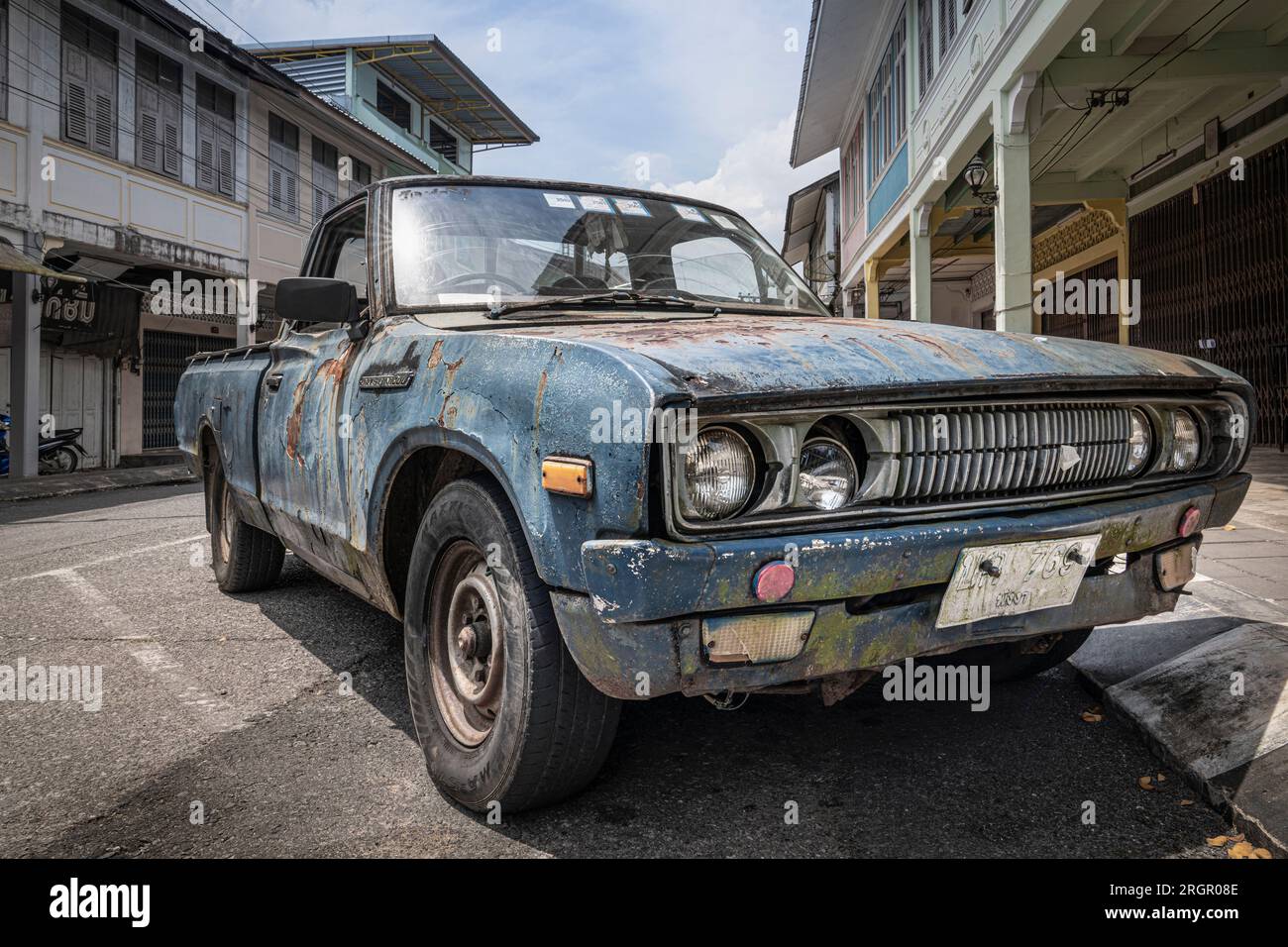 An old, battered and rusty Japanese pickup truck DATSUN close-up on the street in Thailand, in the old town of Takua Pa. Takua Pa Thailand, Phang Nga Stock Photo