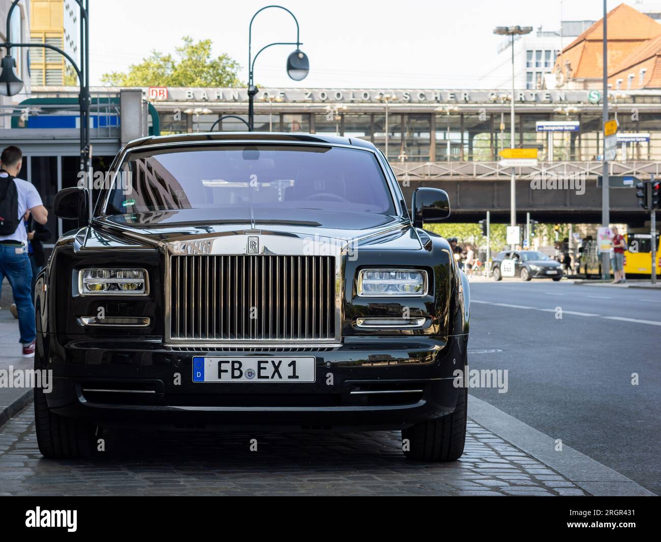 Rolls Royce Phantom luxury car parking next to the street. The black shiny limousine in empty. Buildings of the public transport are in the background Stock Photo
