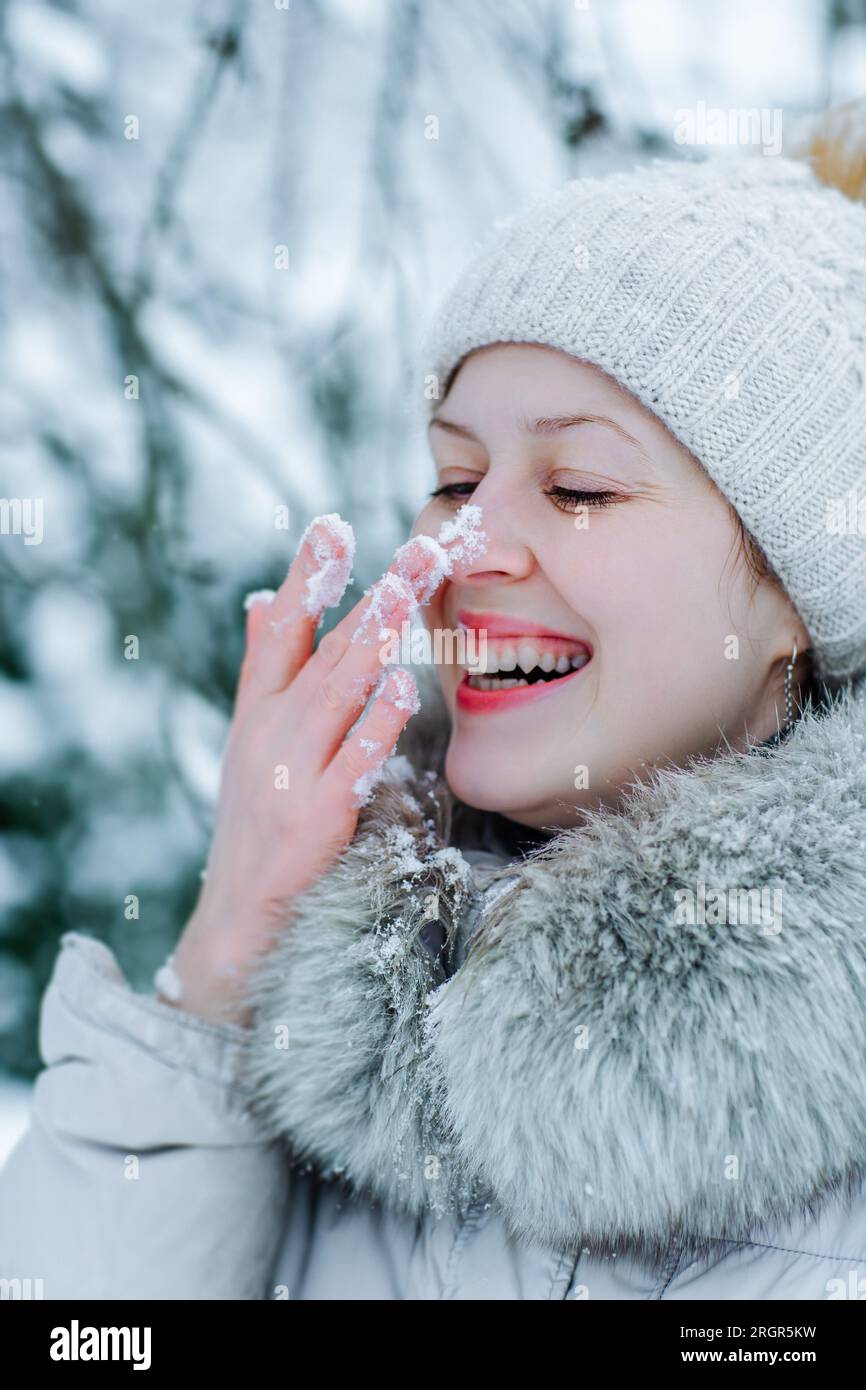 Portrait of young happy woman in warm winter clothing with snow on nose Stock Photo