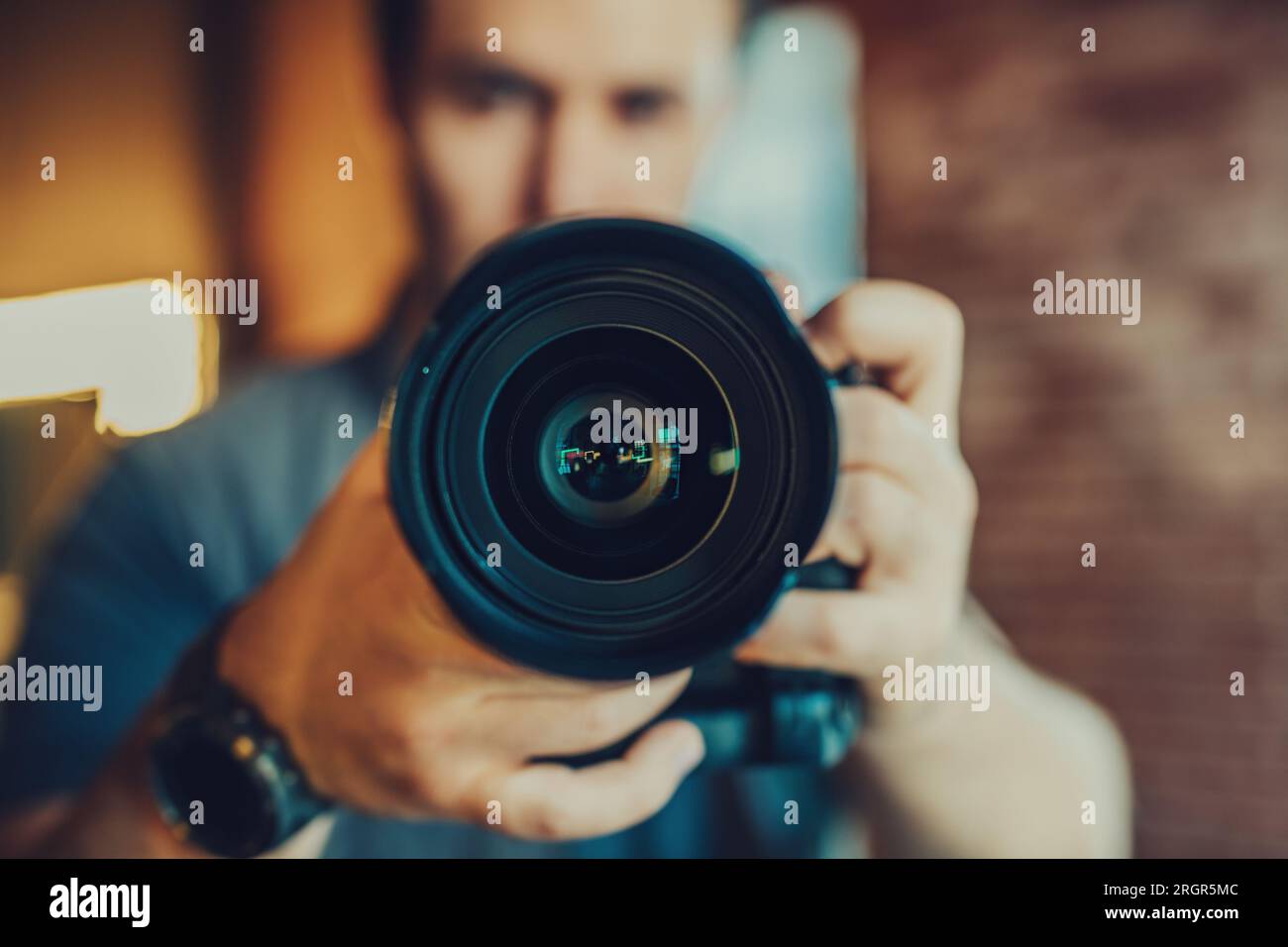 Young man photographer making selfie at mirror, focus on camera lens Stock Photo