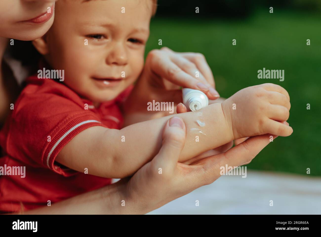 Mother puts cream on baby's hand in summer Stock Photo