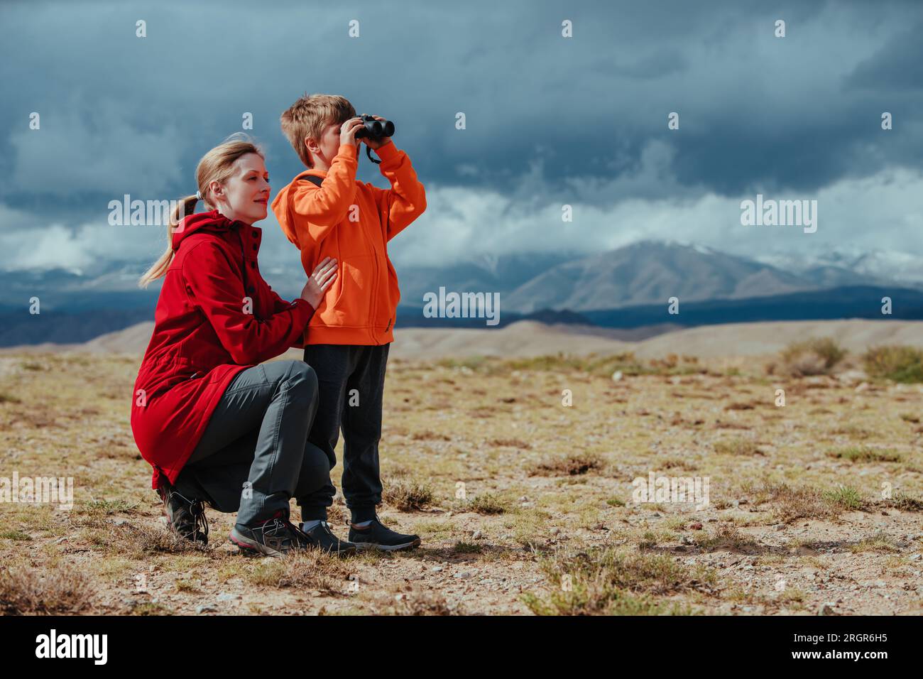 Boy tourist with binoculars and his mother in mountains Stock Photo