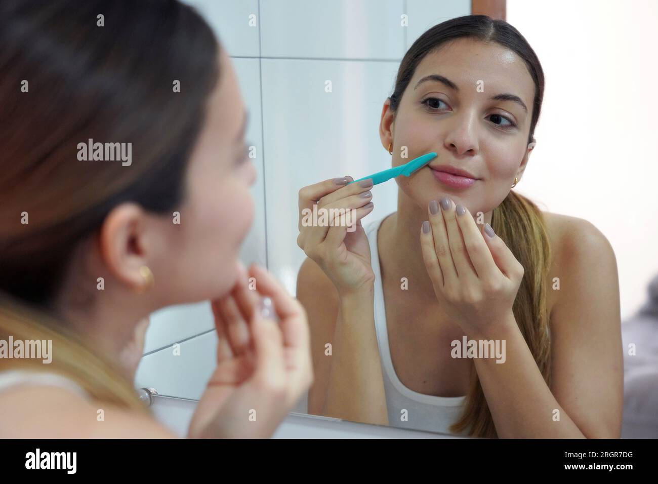 Facial hair removal. Close-up of beautiful young woman shaving her face ...