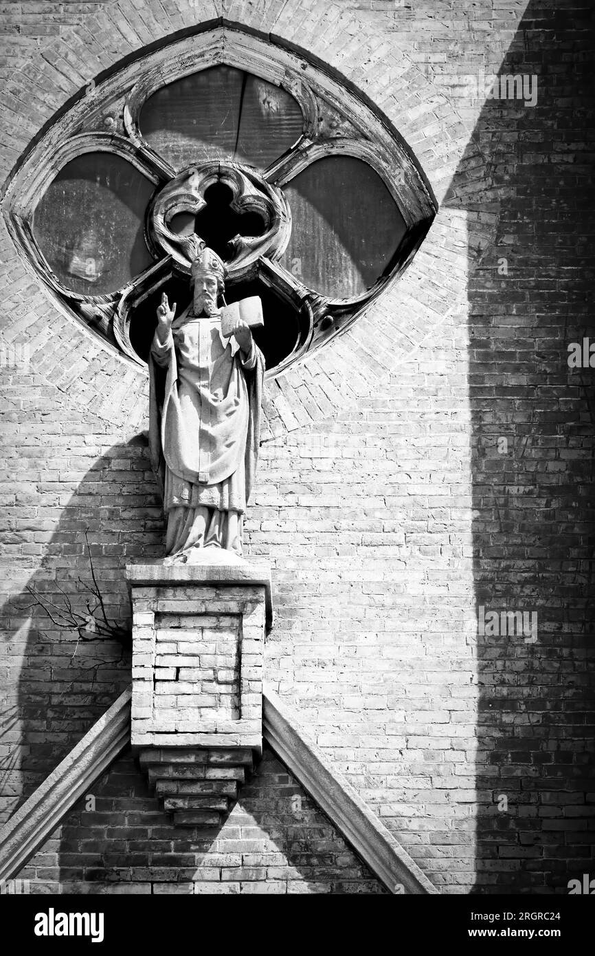 A statue of Saint Ambrose over the entry of the dilapidated Saint