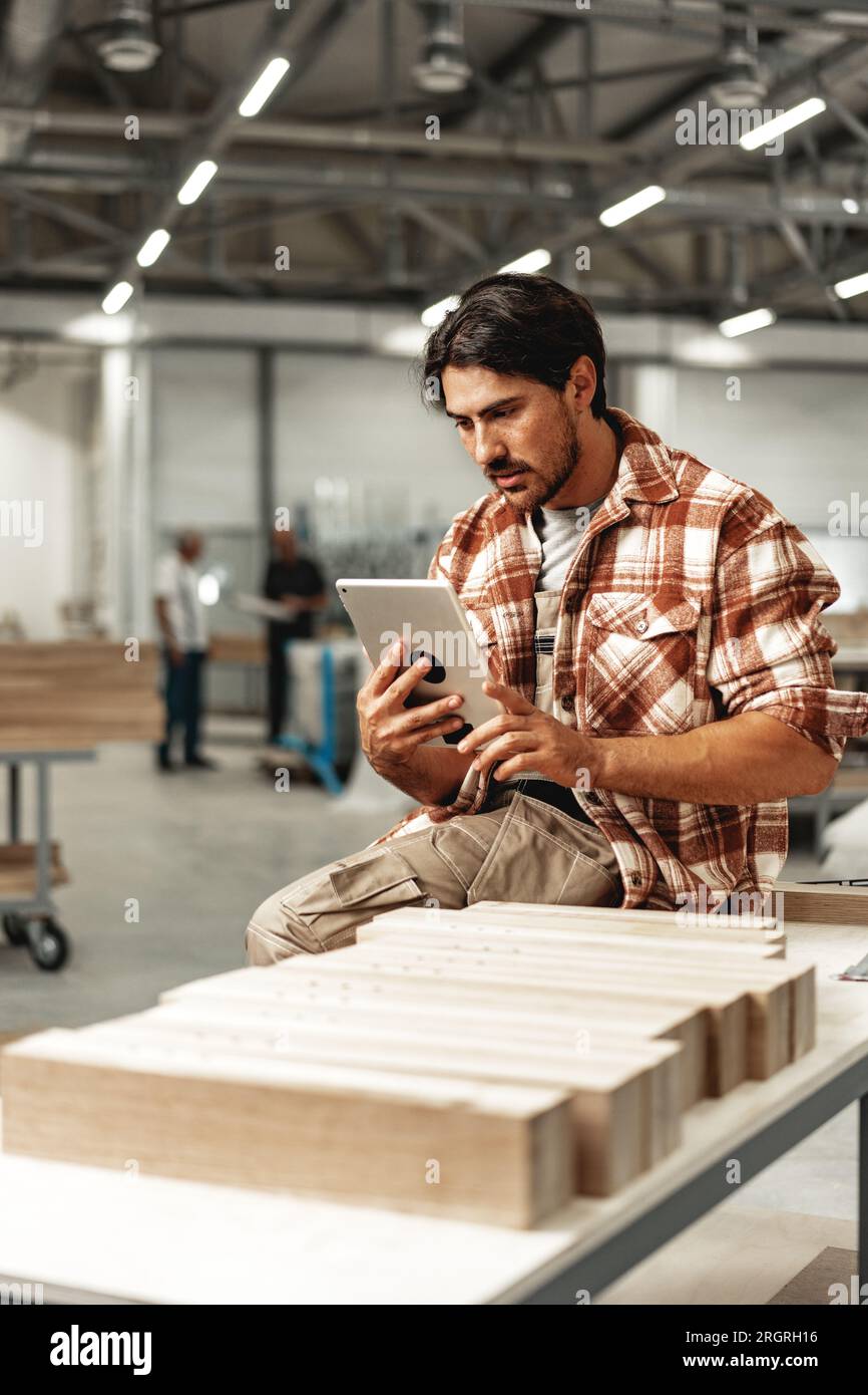 Young carpenter standing in his workshop using a digital tablet Stock Photo