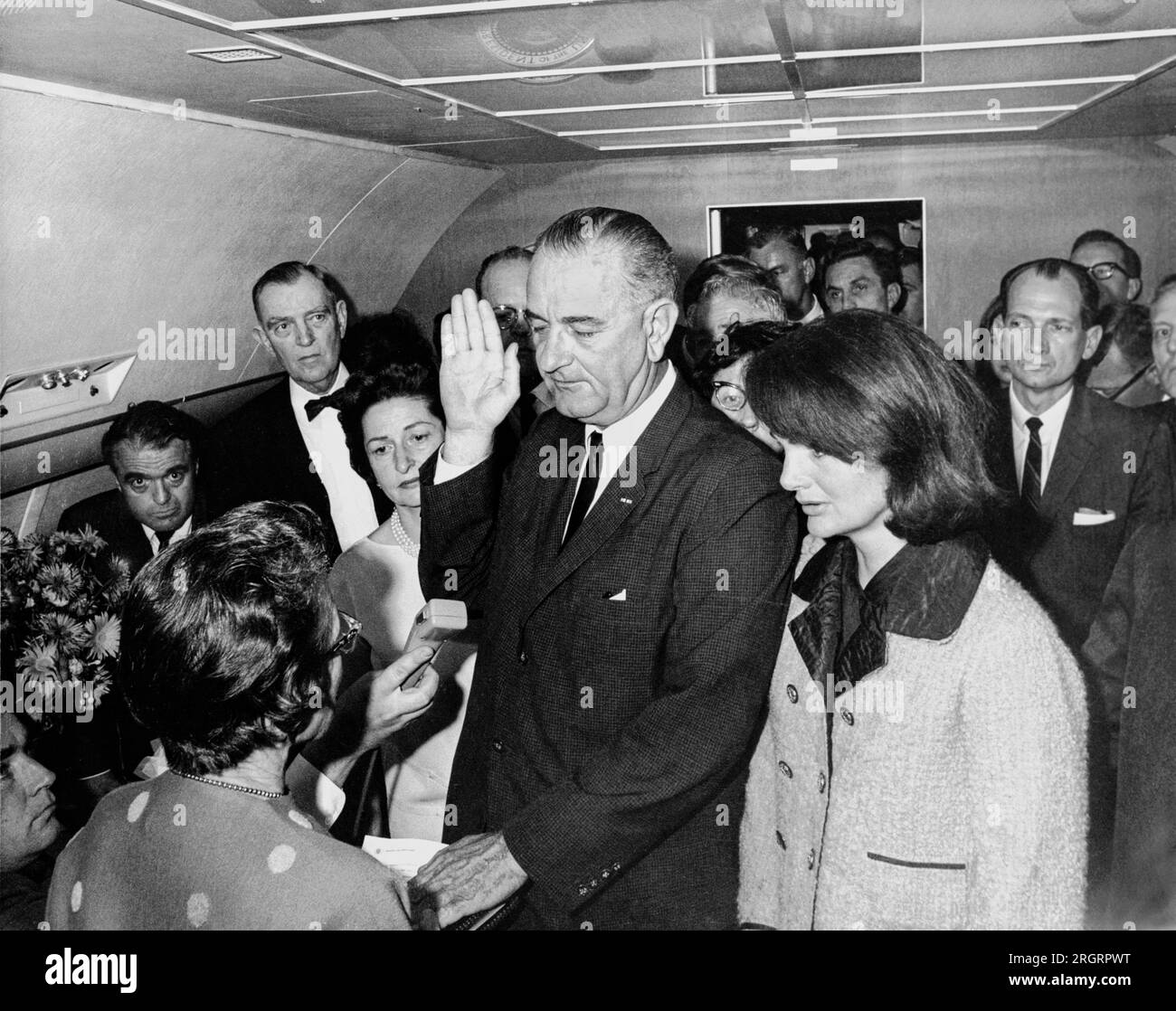 Dallas, Texas: November 22, 1963 Lyndon B. Johnson taking the oath of office on Air Force One at Love Field Airport two hours and eight minutes after the assassination of John F. Kennedy. L-R: Mac Kilduff (holding dictating machine), Judge Sarah T. Hughes, Jack Valenti, Congressman Albert Thomas, Marie Fehmer (behind Thomas), First Lady Lady Bird Johnson, Dallas Police Chief Jesse Curry, President Lyndon B. Johnson, Evelyn Lincoln (eyeglasses only visible above LBJ's shoulder), Congressman Homer Thornberry (in shadow, partially obscured by LBJ), Roy Kellerman (partially obscured by Thornberry) Stock Photo