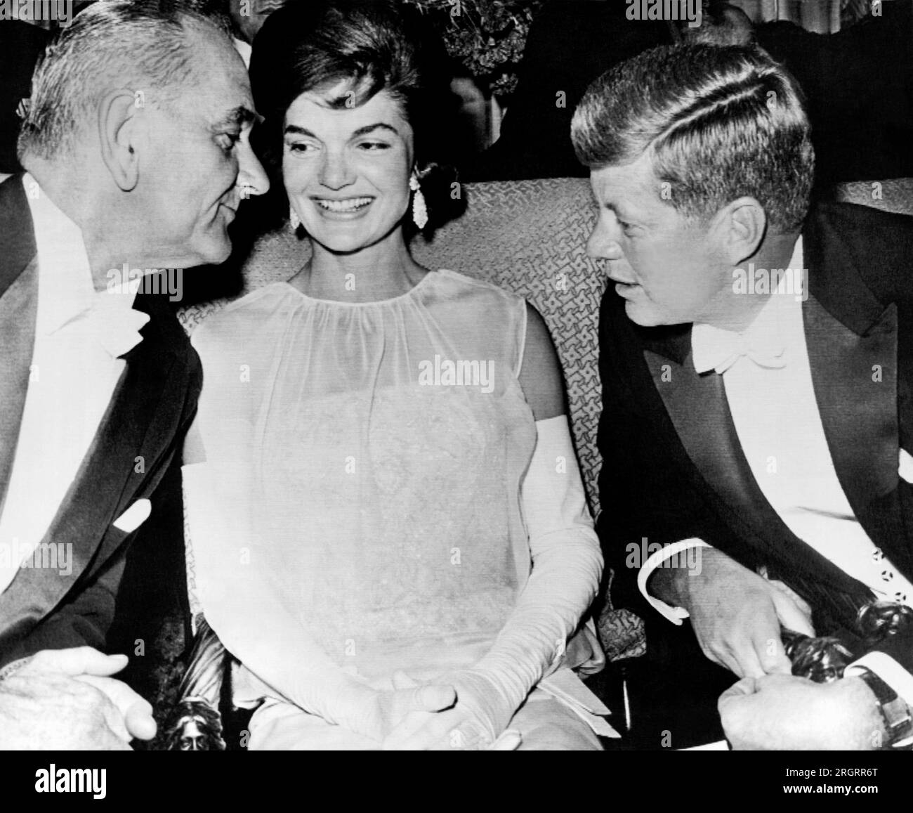 Washington, D.C.:   February 2, 1961 Vice President Lyndon Johnson leans over Jacqueline Kennedy to listen to President John Kennedy at the inaugural ball after their election to office. Stock Photo