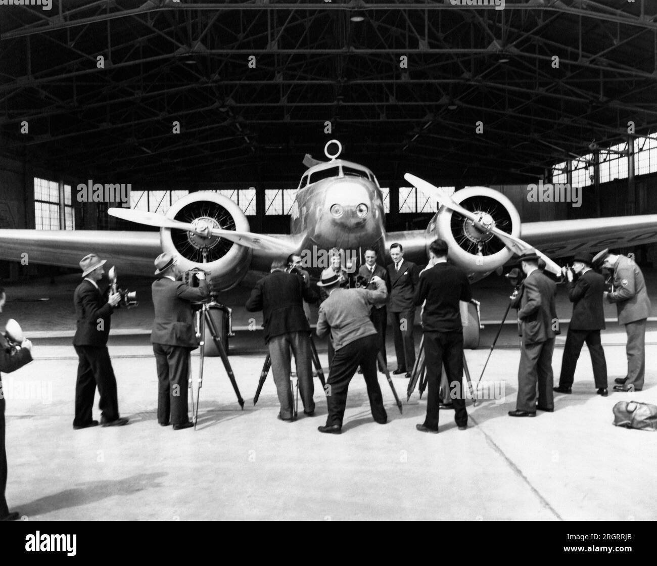 United States:  1937 Photographers taking photos of (L-R), Paul Mantz, Amelia Earhart, Harry Manning, and Fred Noonan, all posed in front of Earhart's Lockheed Electra 10E Stock Photo
