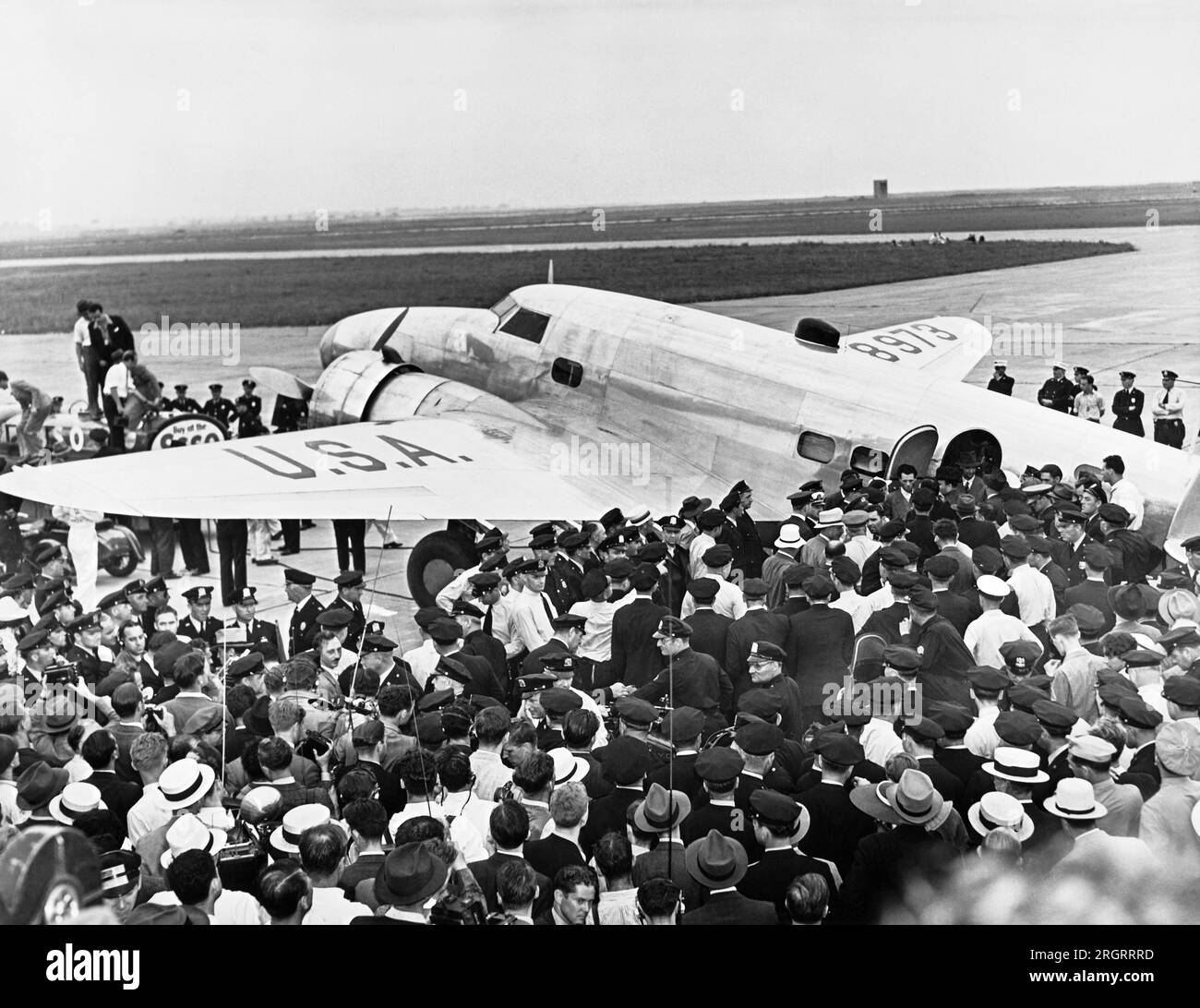 New York, New York:  July 14, 1938 Police surround Howard Hughes' Lockheed 14N Super Electra airplane at Floyd Bennett Airport in Brooklyn when he landed there after flying around the world setting a new record of 3 days, 19 hours and 14 minutes, breaking Wiley Posts's record. It was part of a promotion to attract people to the New York World's Fair. Stock Photo