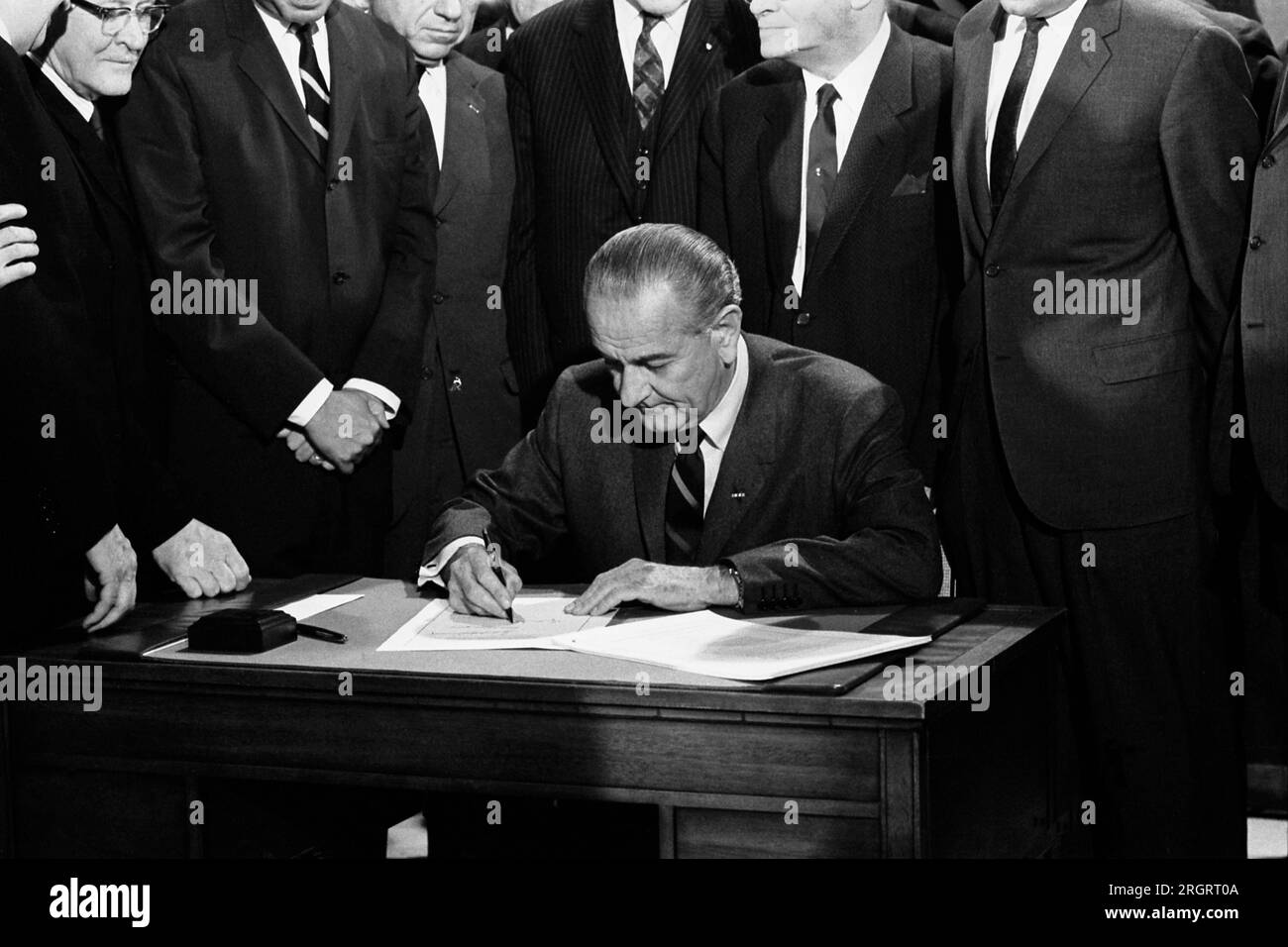 Washington, D.C.:  April 11, 1968 President Lyndon Johnson signs the Civil Rights bill while seated at a table surrounded by members of Congress. Stock Photo