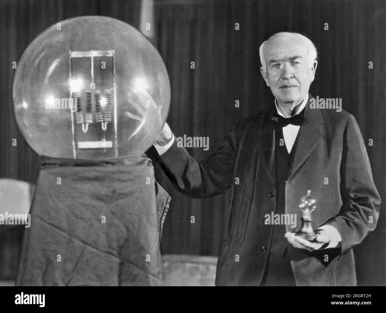 Orange, New Jersey:  October 16, 1929 Noted inventor Thomas Edison at the lightbulb's golden jubilee anniversary banquet in his honor. He is exhibiting in his hand a replica of his first  successful incandescent lamp which gave 16 candlepower of illumination, in contrast to the latest lamp, a 50,000 watt, 150,000 candlepower lamp. Stock Photo