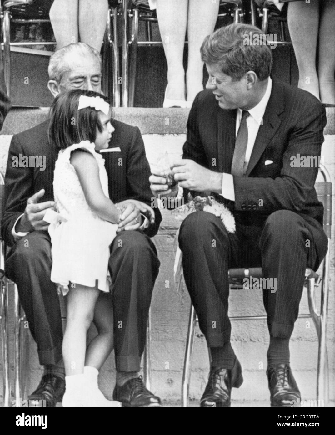 Mexico City, Mexico:  June 30, 1962 President Kennedy thanks a little Mexican girl who gave him a bouquet of flowers at a Fourth of July celebration for the American colony in Mexico City today. With the girl is Gustavo Bas, governor of the state of Mexico. Stock Photo