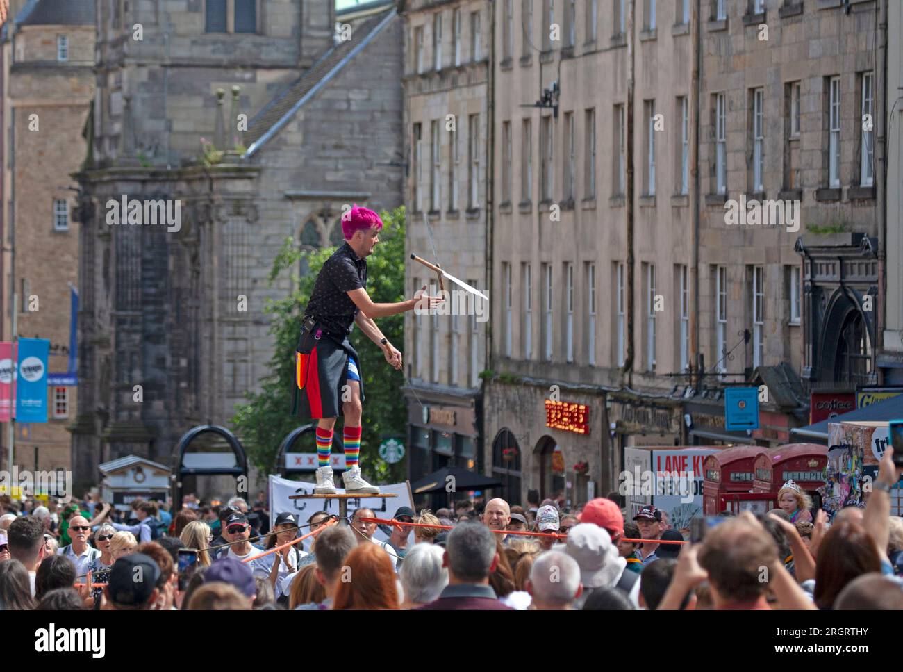 Royal Mile, Scotland, UK. 11 August 2023. Street Performers on High Street finding the windy conditions difficult but hot weather welcome with temperature just over 20 degrees. Crowds arriving later in the day with several other performing pitches around the city centre. Pictured: Super Scott entertains with his knife juggling act. Credit: Archwhite/alamy live news. Stock Photo