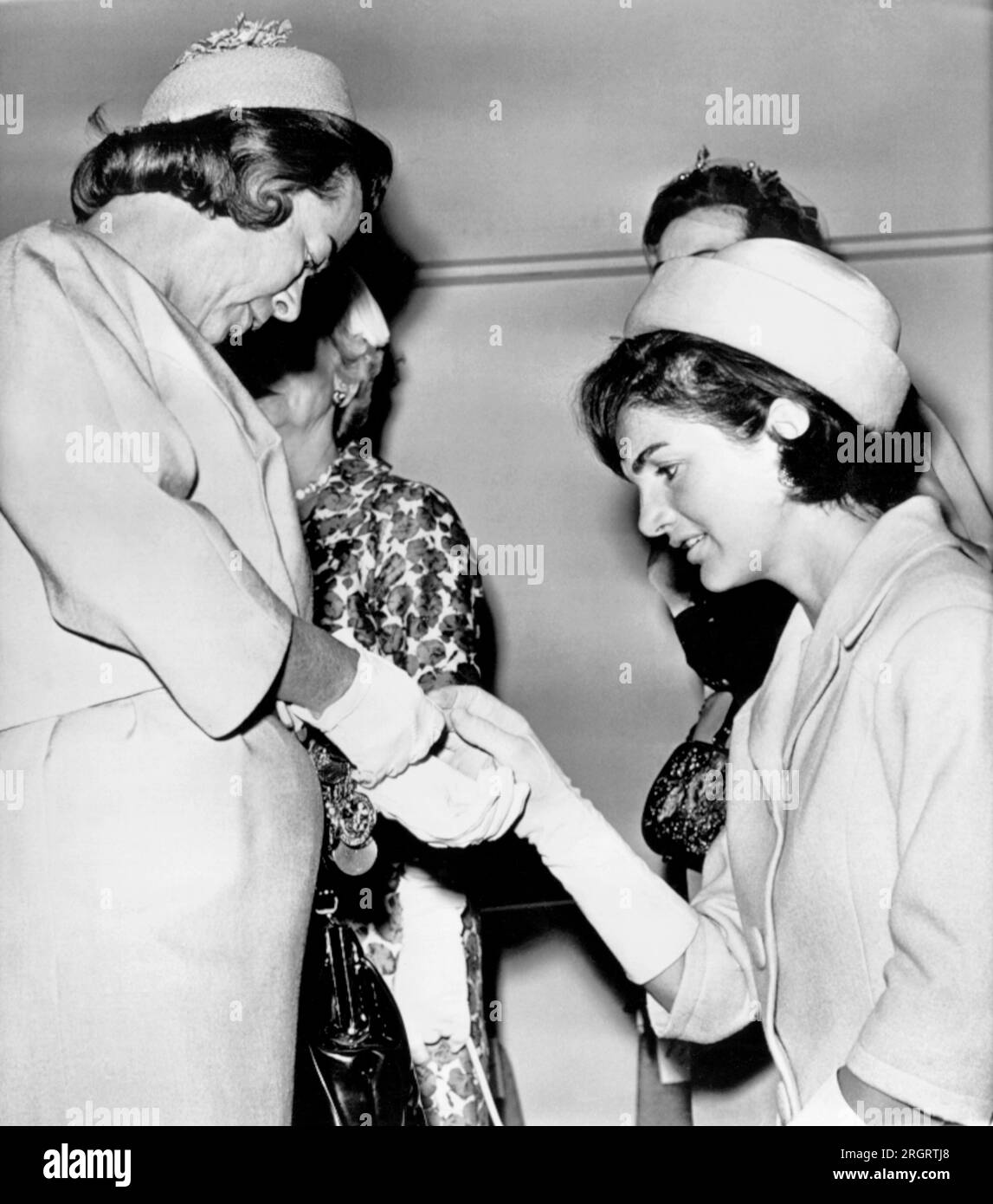 Washington, D.C.:  May 18, 1961 Mrs. Jacqueline Kennedy inspects a gold bracelet worn by Mrs.Barry Goldwater at a luncheon given for Mrs. Kennedy by wives of the members of Congress. Stock Photo