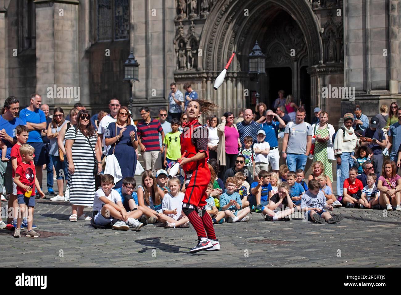 Royal Mile, Scotland, UK. 11 August 2023. Street Performers on High Street finding the windy conditions difficult but hot weather welcome with temperature just over 20 degrees. Crowds arriving later in the day with several other performing pitches around the city centre. Pictured: Chirimbolo from Argentina juggles clubs in Parliament Square. Credit: Archwhite/alamy live news. Stock Photo