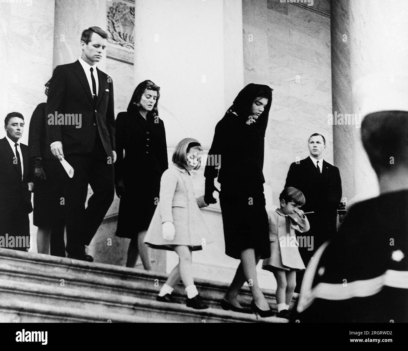 Washington, D.C.:  November 25, 1963 The President's family leaves the Capitol after the funeral ceremony. Front row: Caroline Kennedy, Jacqueline Bouvier Kennedy, John F. Kennedy, Jr. (2nd row) Attorney General Robert F. Kennedy, Patricia Kennedy Lawford (hidden) Jean Kennedy Smith (3rd Row) Peter Lawford. Stock Photo