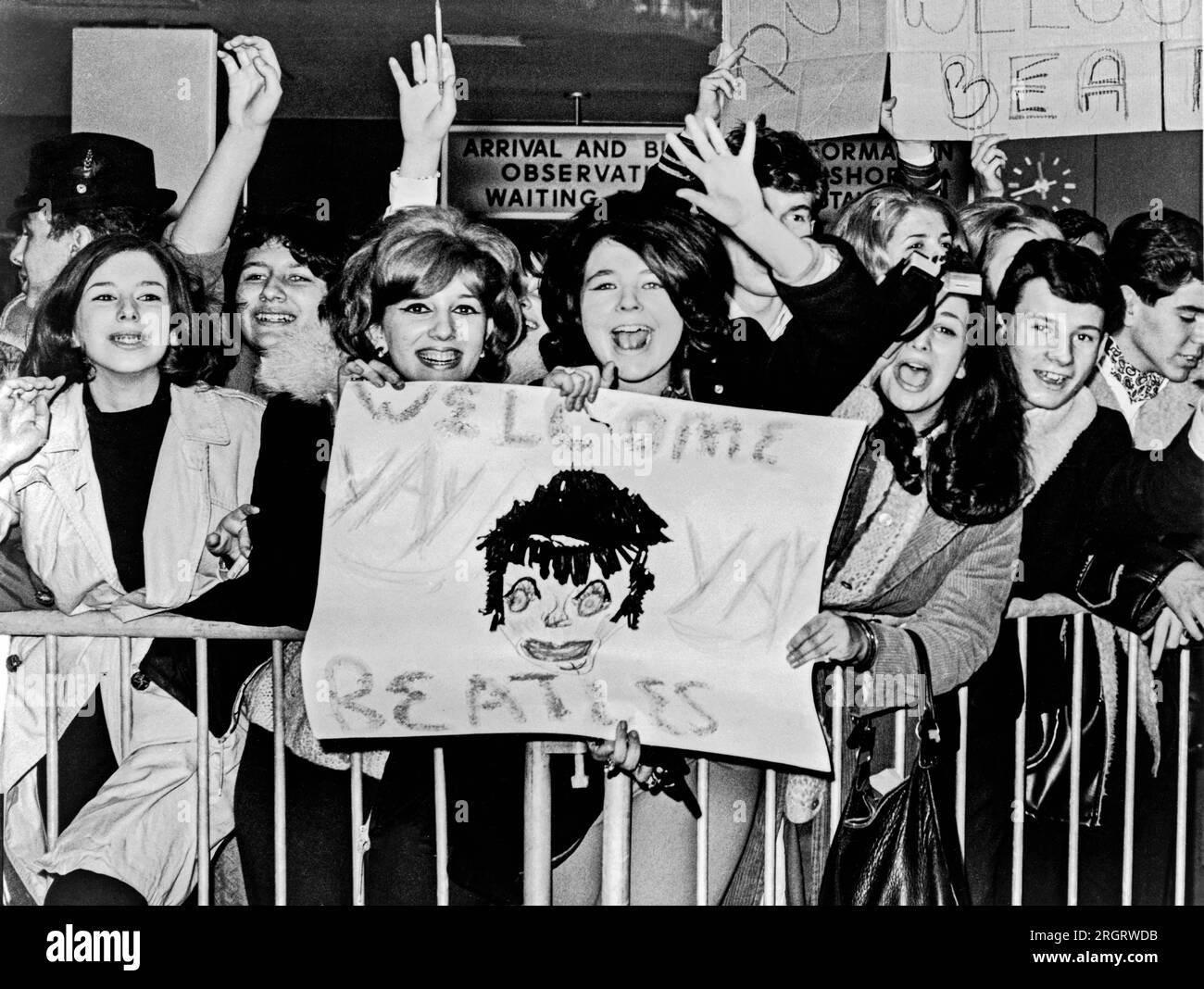 New York, New York:  February 7, 1964. Screaming teenagers wave a crude sign as they welcome 'The Beatles' - Britain's shaggy-haired rock n' roll singers - upon their arrival at New York's John F. Kennedy Airport. Stock Photo