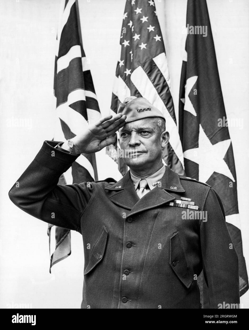 United States:  c. 1943 Four star General Dwight D. Eisenhower stands and salutes the flag. Stock Photo