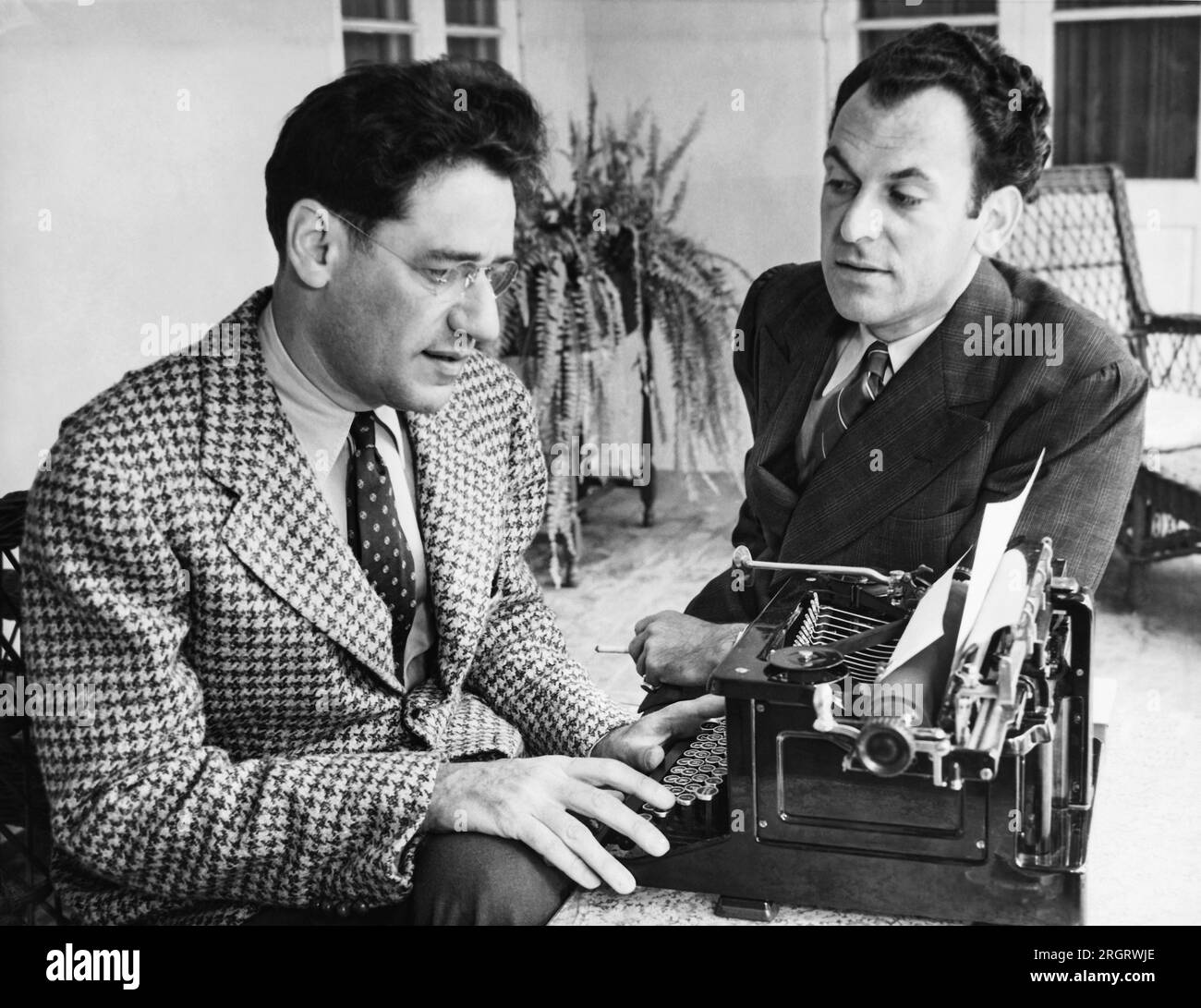 United States:  May 6, 1937 Noted playwrights George S. Kaufman and Moss Hart with Kaufman at a typewriter. The two men collaborated on numerous plays. Stock Photo