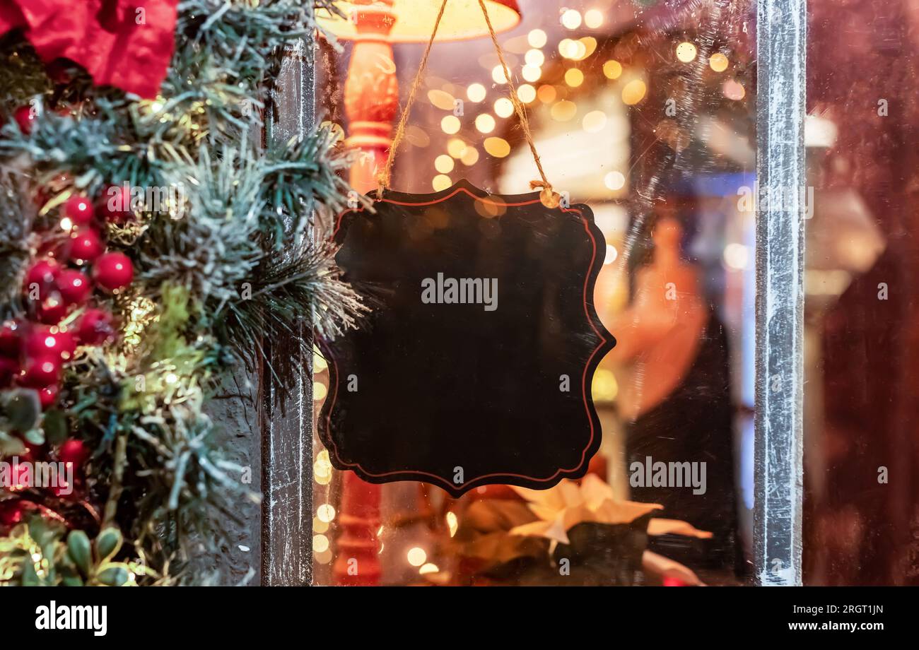 Empty blank black signboard, sign board hanging on cafe or shop window, decorated for Christmas holiday. Stock Photo
