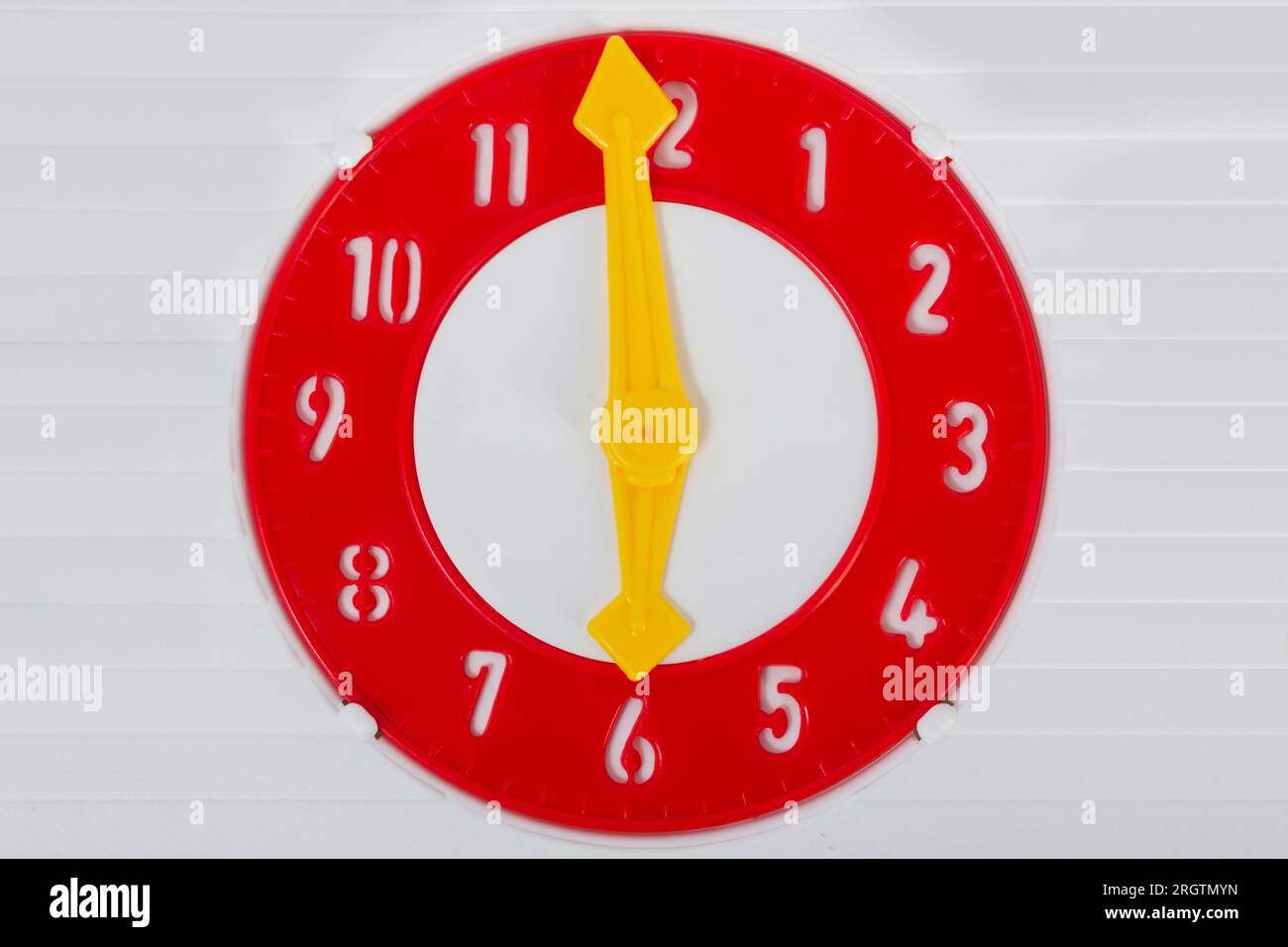 Photo of plastic red colored kids toy clock with yellow clock hands on
