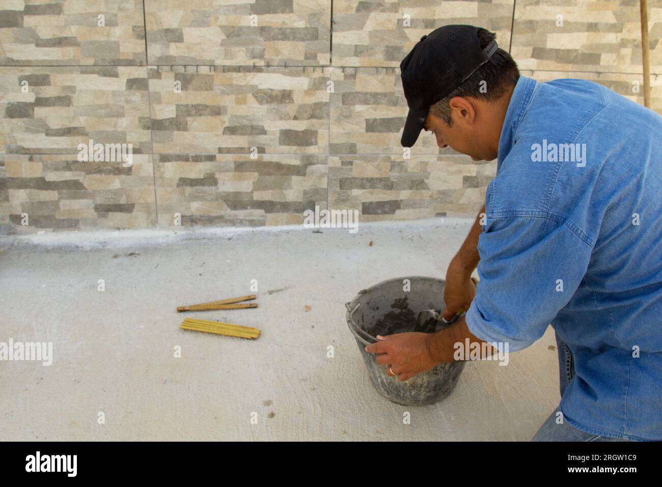 Image of a bricklayer mixing cement and glue in a bucket. Manual work