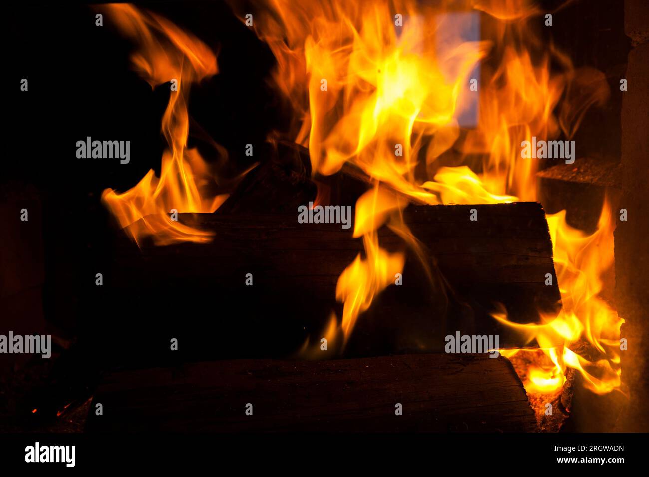 burning logs in the fire of a barbecue or stove or fireplace, the flame of the fire burns dry logs releasing heat and heating the room, close up of th Stock Photo