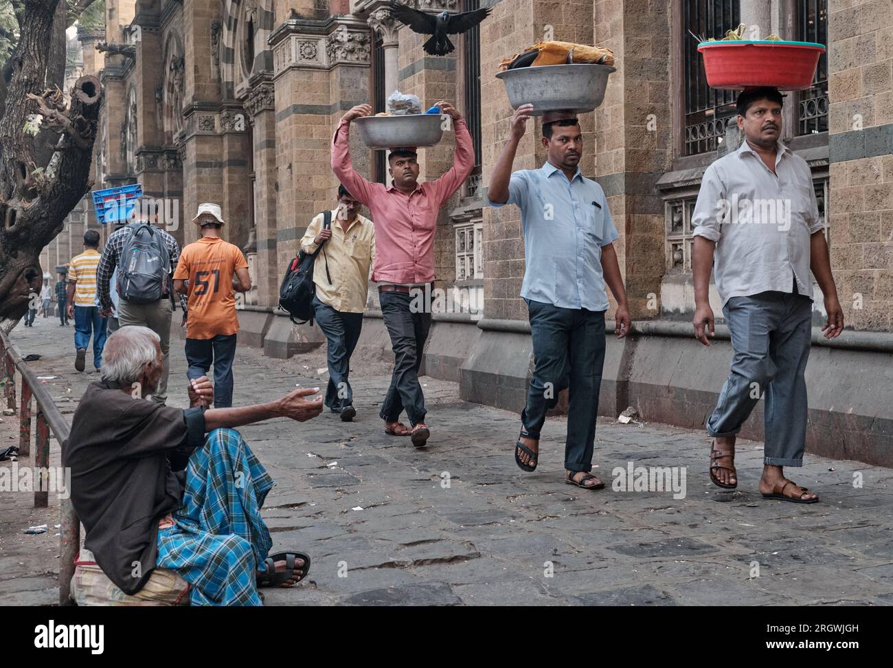 Porters with trays of fish on their heads, outside Chhatrapati Shivaji Maharaj Terminus (CMST), in Mumbai, India, to forward the trays by local train Stock Photo