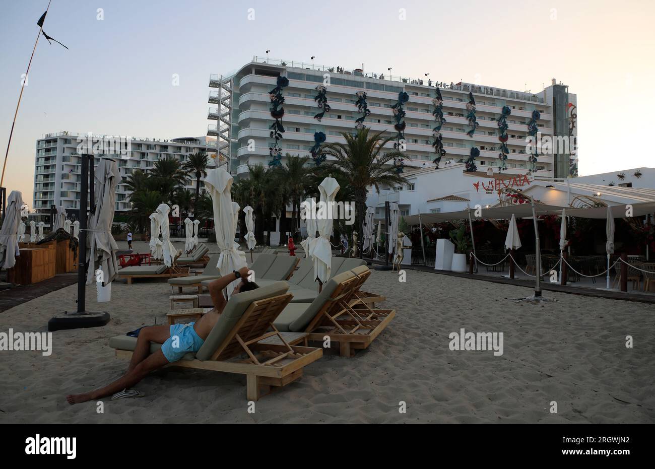 11 August 2023, Spain, Sant Josep De Sa Talaia: A vacationer sits on a lounger near the Ushuaia Hotel in Ibiza. Photo: Clara Margais/dpa Credit: dpa picture alliance/Alamy Live News Stock Photo