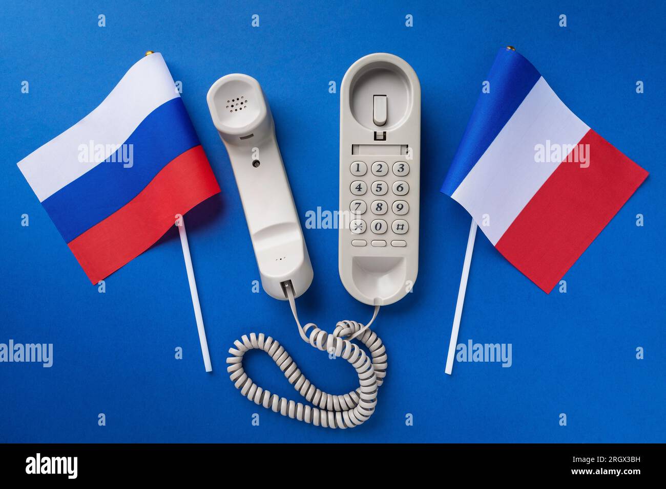 An old telephone and two flags on a blue background, a concept on the topic of telephone conversations between France and Russia Stock Photo