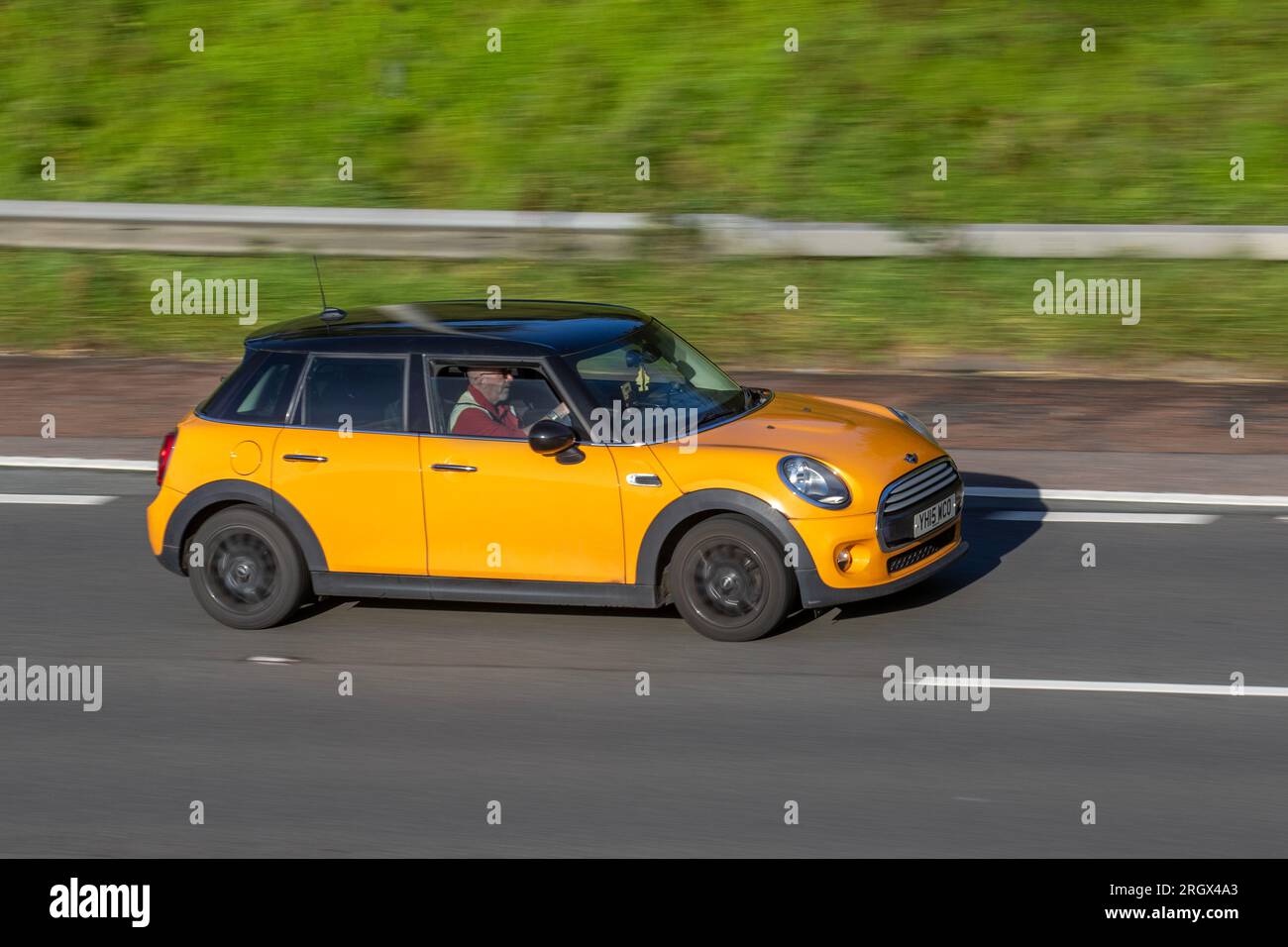 2015 Mini Cooper Auto Steptronic Auto Orange Car Hatchback PetroL 1499 cc, double-clutch 6d; travelling at speed on the M6 motorway in Greater Manchester, UK Stock Photo
