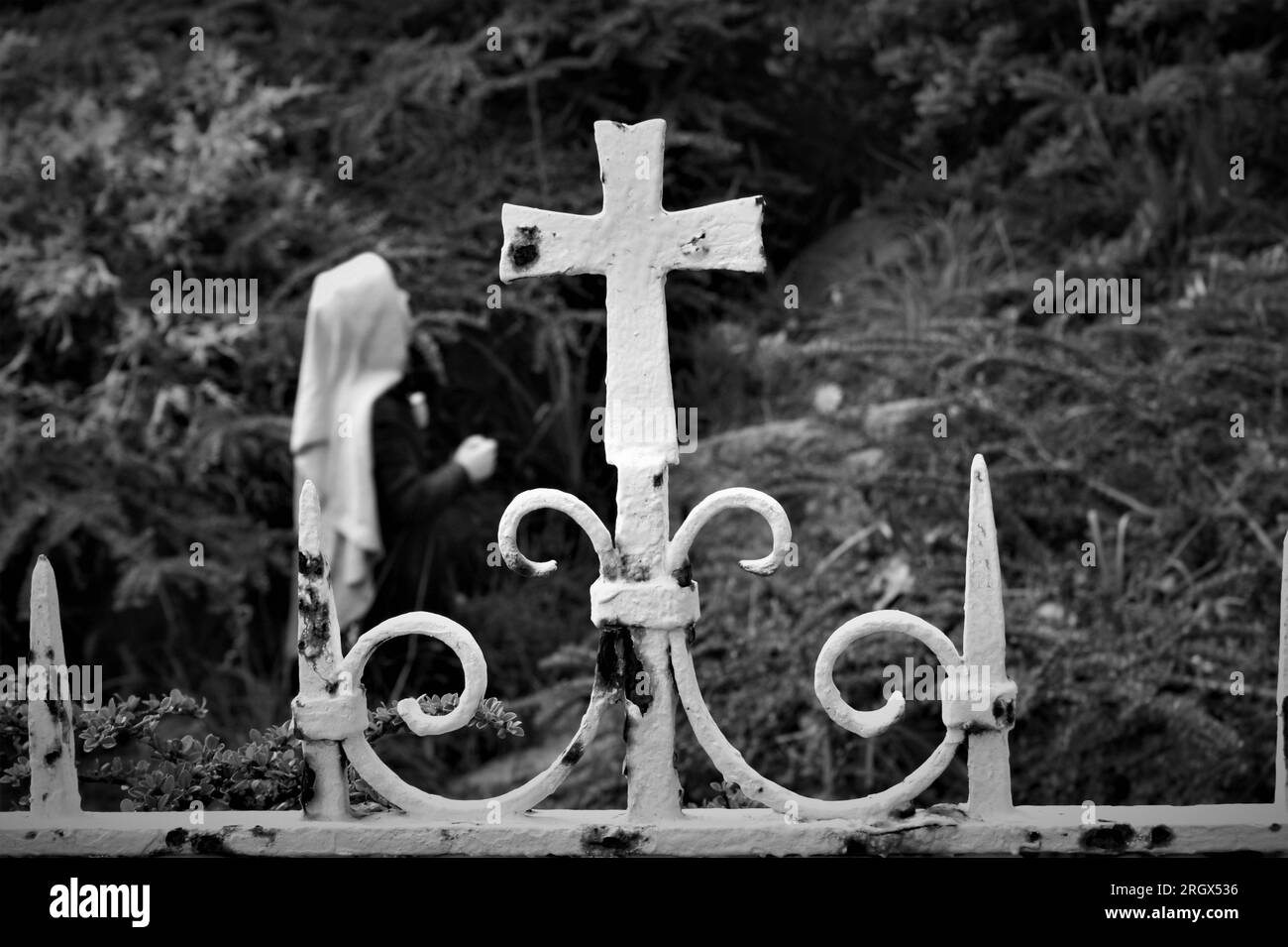 A fragment of an old metal fence. Old metal fence with a cross near the