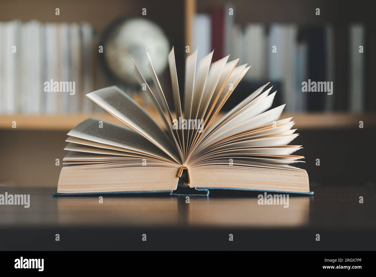 Education learning concept. Book in library with old open textbook, stack piles of literature text archive on reading desk, aisle of bookshelves in sc Stock Photo