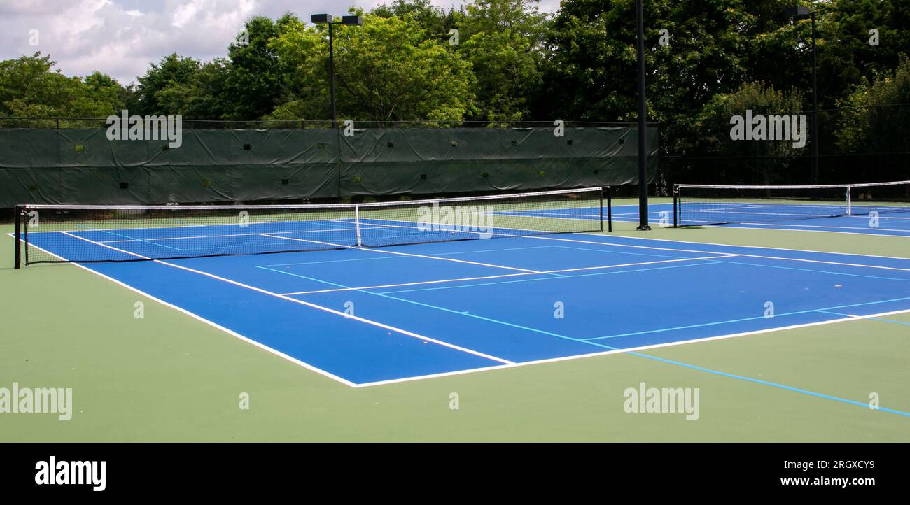 Wide view of two blue and green tennis courts that are also lined for pickleball games. Stock Photo