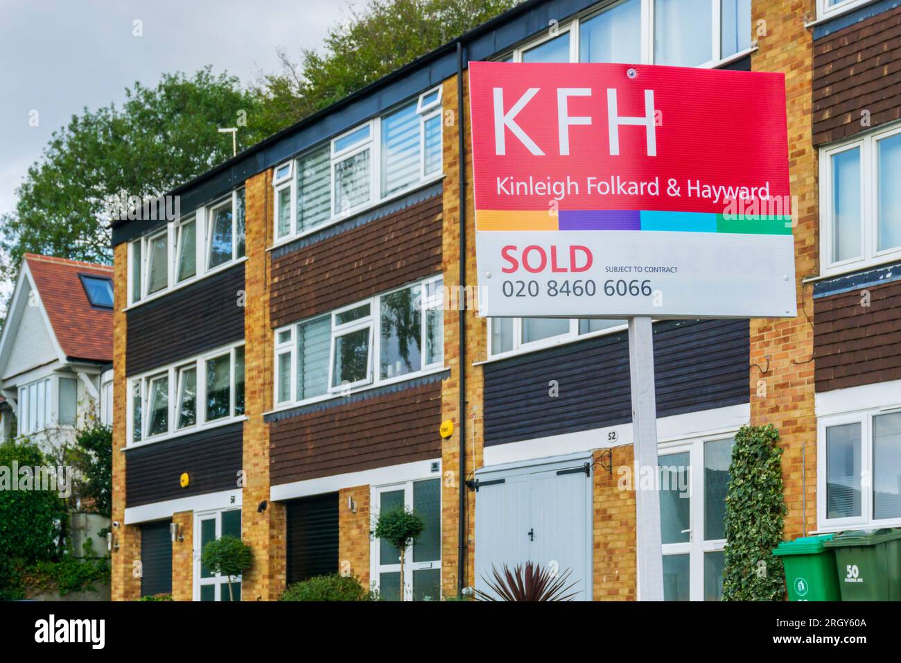An estate agents Sold sign outside a terrace of three storey town