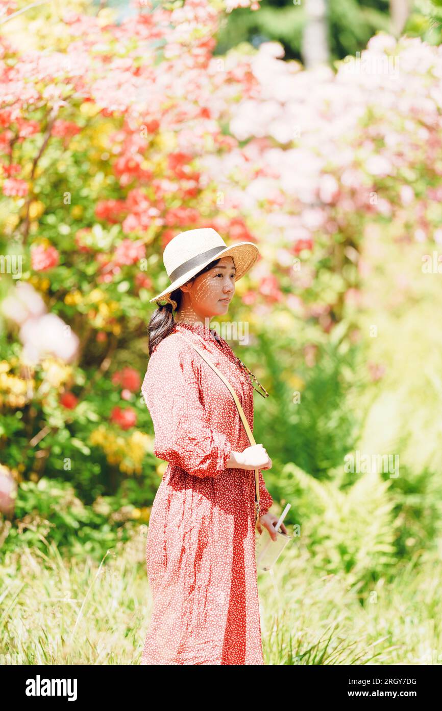 A woman in a red dress standing in a garden Stock Photo