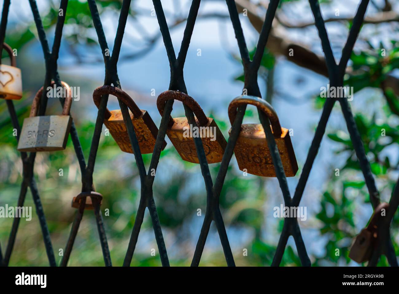 A mesh fence on the seashore with padlocks symbolizing love. Love locks are hung on the fence in large numbers on the sea promenade. Sea on background Stock Photo