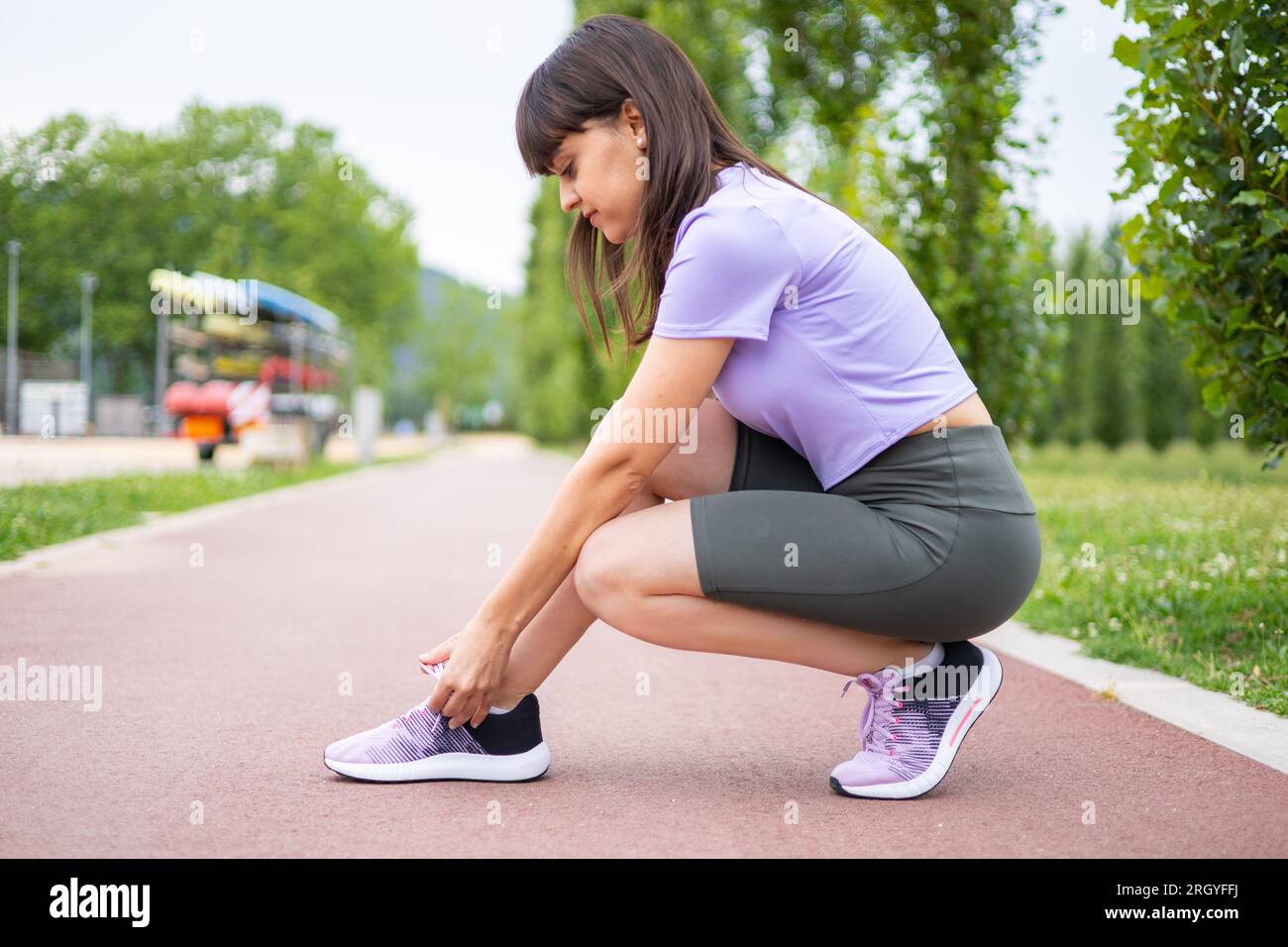 Female athlete tying running shoe laces for running workout. Fitness training outdoors. Exercise and active lifestyle. Stock Photo