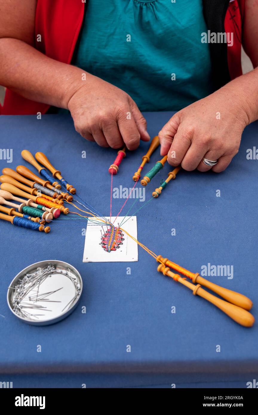 Hands of people preparing and making bobbin lace. Colorful lace threads. Leisure activity. Stock Photo