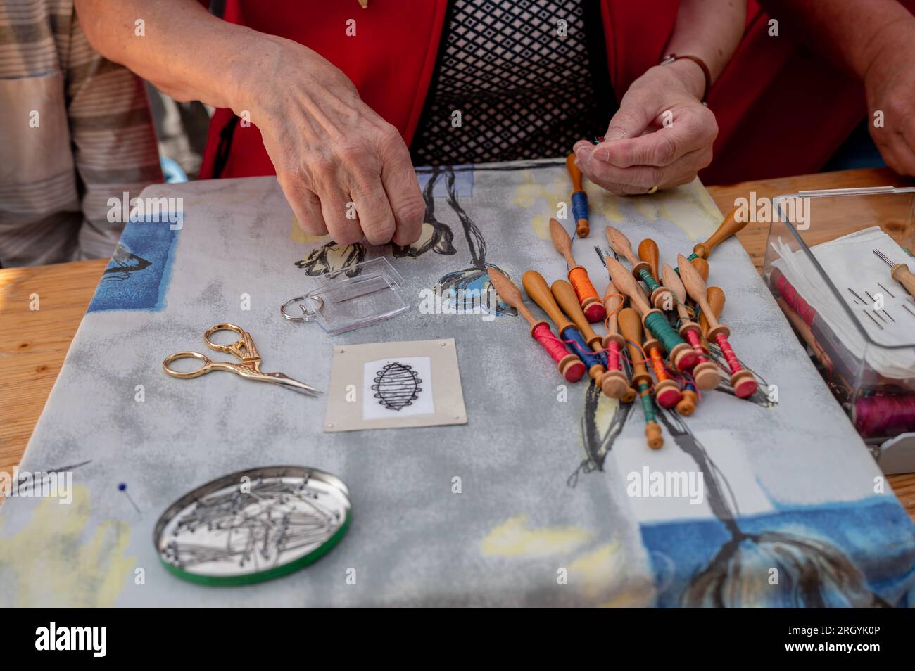 Hands of people preparing and making bobbin lace. Colorful lace threads. Leisure activity. Stock Photo