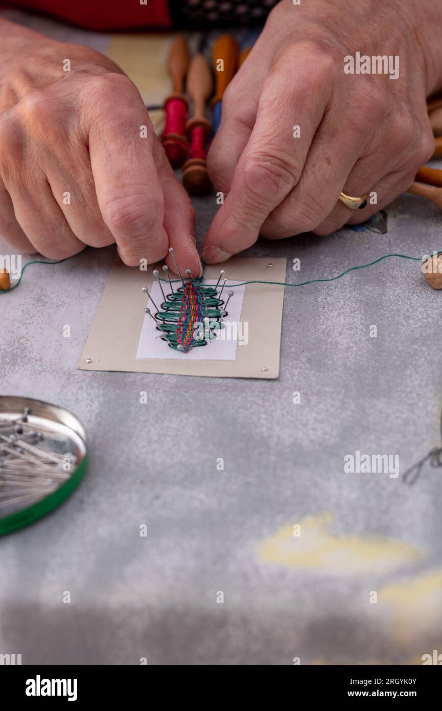 Hands of people preparing and making bobbin lace. Colorful lace threads. Leisure activity. Stock Photo