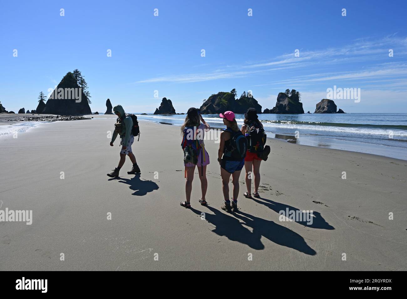 Hikers on Shi Shi Beach Trail in Olympic National Park near Neah Bay, Washington on sunny summer afternoon with Point of Arches in background. Stock Photo