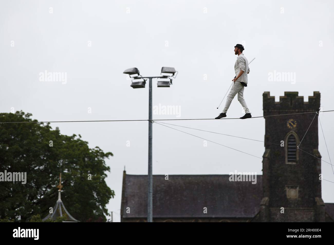 Carmarthen, UK. 12 August, 2023. Carmarthen-born high wire walker Ellis Grover walks the length of the rugby pitch (100m) in Carmarthen Park at a height of 10m without a safety rope or net.  Ellis started honing his skills as a teenager at Carmarthen Park, where he would balance along the railings that surround the park’s velodrome.  Credit: Gruffydd Thomas/Alamy Stock Photo